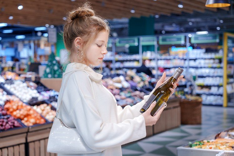 Девушка выбирает вино в магазине