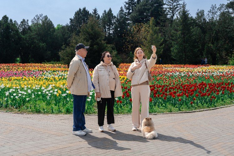 люди фотографируются на фоне цветов